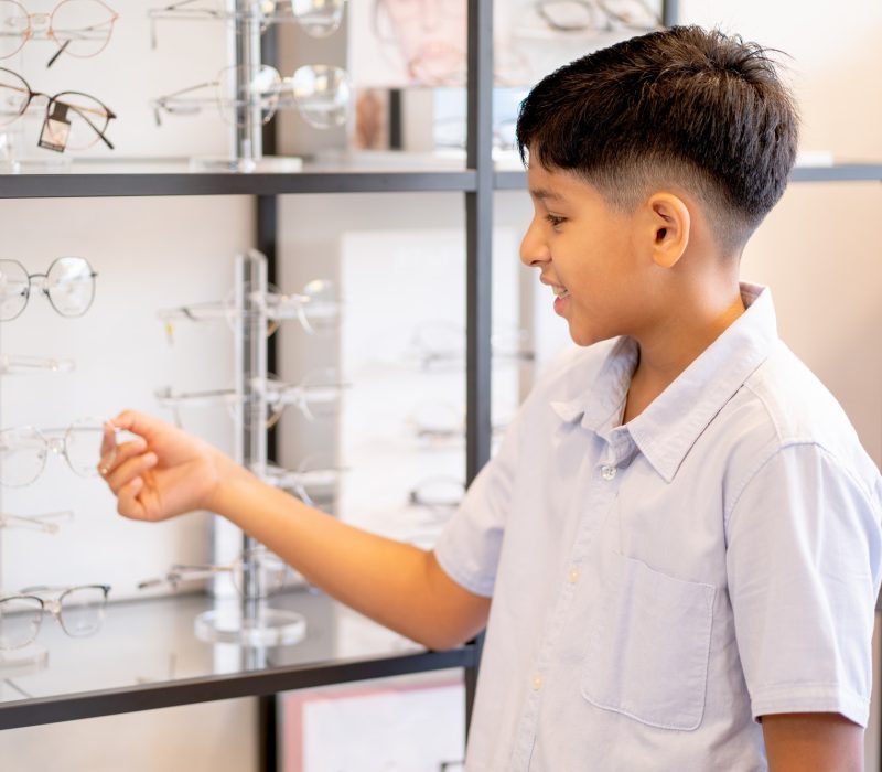 indian-boy-hold-glasses-on-shelf-during-selection-to-buy-some-products-for-his-eyecare.jpg